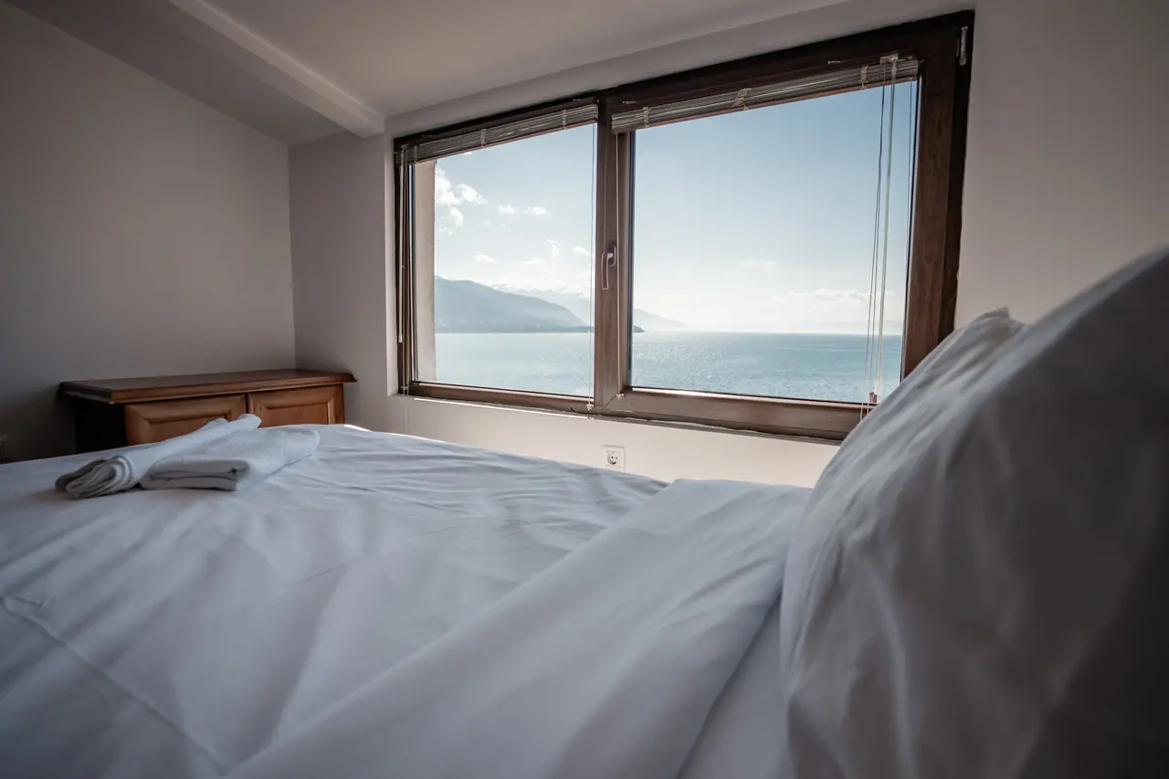 The Penthouse bed facing a wide window onto the lake and mountains